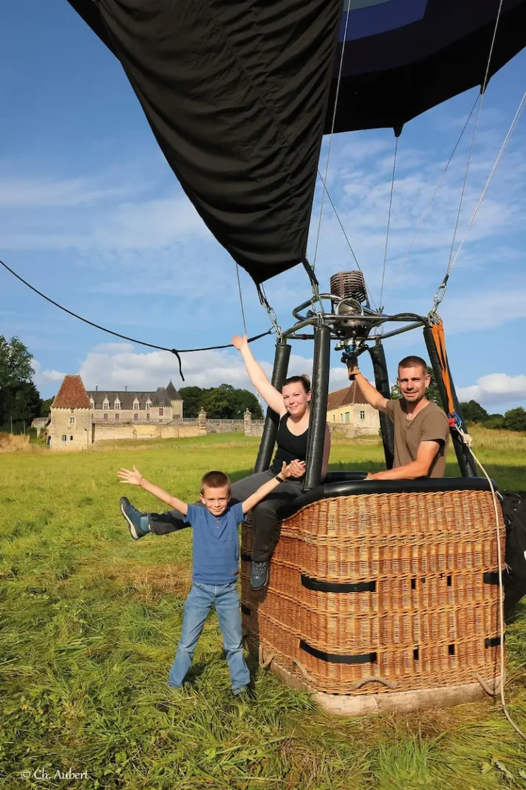 Famille posant dans le panier de la montgolfière de L'Air du Perche, avec un château en arrière-plan.